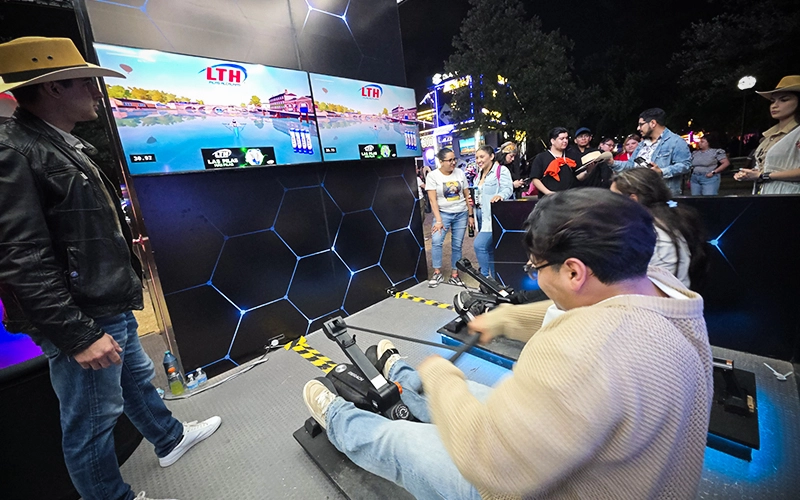 Participante en una bicicleta interactiva frente a una pantalla con una carrera virtual