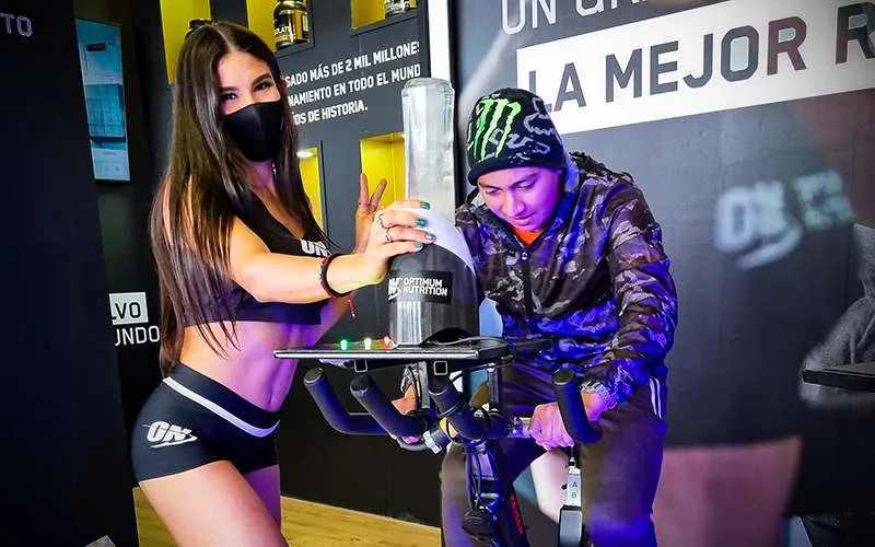 Participante pedaleando para activar un dispensador de producto en una activación de Optimum Nutrition