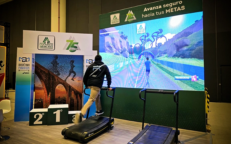 Participante pedaleando frente a una pantalla con una carrera virtual en una activación de ZTE